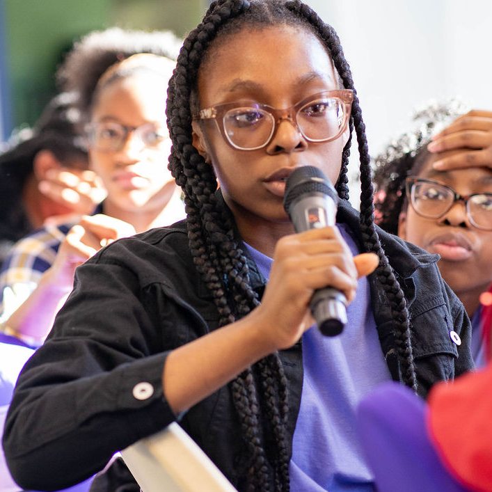 A girl speaking into a microphone during a forum discussion